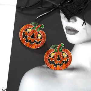 Détail de boucles d'oreilles citrouille d'Halloween avec cristaux oranges et émail
