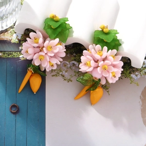 Détail de boucles d'oreilles florales avec pétales roses et pendentifs gouttes jaunes