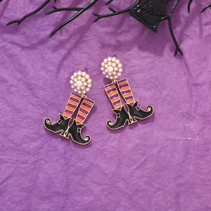 Halloween witch boot earrings with purple stripes, pearls and black boots on purple background