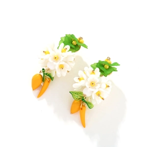Détail de boucles d'oreilles à fleurs en résine blanche et pampilles carottes jaunes
