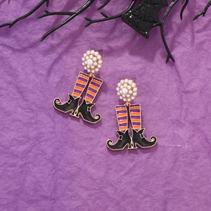 Detail of Halloween witch boot earrings with purple stripes and pearl cluster on purple background