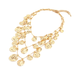 Close-up of triple-layered gold necklace featuring hammered irregular coin pendants