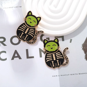 Pair of Halloween black cat enamel pins with green eyes and golden skeleton details