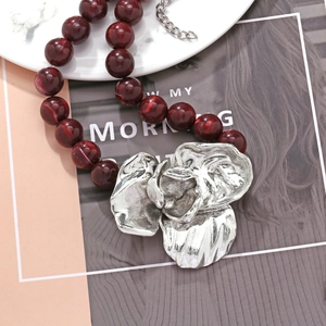 Macro detail of vintage red marble beads and oversized silver flower pendant necklace