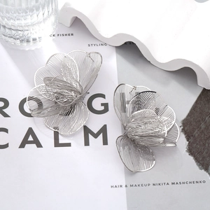 Modern oversized silver floral earrings with hollow petal layers on minimalist background