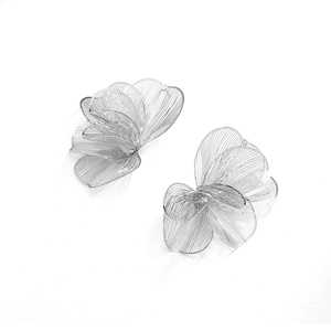 Macro detail of silver woven metal wire petals on large floral statement earrings