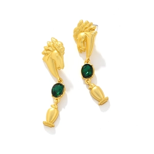 Detail of vintage matte gold horse head earrings with a faceted green glass drop