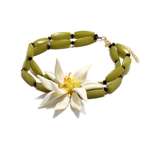 Détail du collier avec grande fleur blanche en résine, perles vertes et fermoir doré