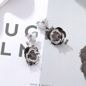 Detail of silver rose earrings with layered petals and a white imitation pearl stud