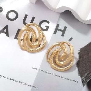 Vintage golden spiral hollow hoop earrings with textured hammered finish on fashion magazine