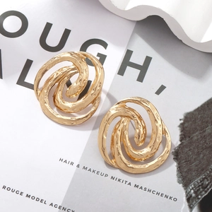 Detailed view of gold spiral swirl earrings with textured hammered finish on white prop