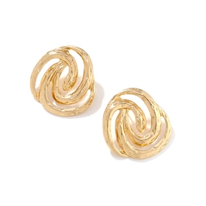 Macro detail of gold spiral earrings with textured hammered finish and layered design