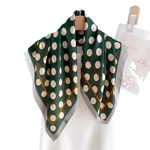 Retro dark green silk scarf with large white polka dots and orange edge on wooden hanger