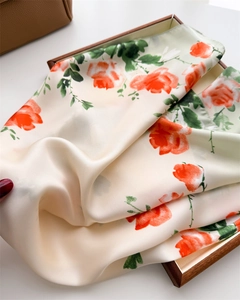 Détail d'un foulard en soie aux imprimés roses plié dans un coffret cadeau de qualité