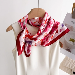 Close-up of elegant floral silk scarf with red contrast border on a white dress