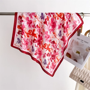 Detail of red floral printed silk scarf draped on a rack with a textured metal chain bag
