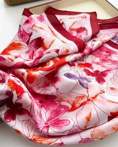 Close-up of elegant floral silk scarf showing artistic red flower patterns and fine texture