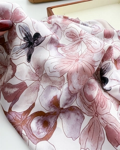 Detailed close-up of floral print silk scarf showing soft texture and glossy fabric