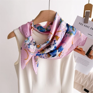 Gros plan sur l'élégant foulard en soie rose avec motifs floraux bleus et lignes jaunes