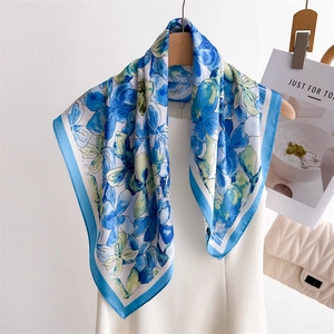 Elegant floral silk square scarf with blue and green patterns on a minimalist hanger