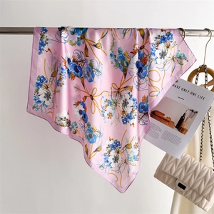 Détail du foulard en soie rose avec motifs floraux bleus et fini brillant élégant