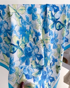 Detail of elegant floral silk scarf featuring blue and green watercolor flower patterns