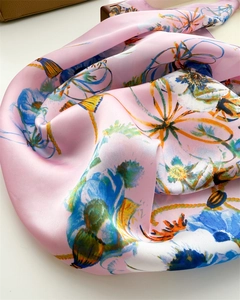 Gros plan d'un foulard en soie rose avec motifs floraux et détails de cordes nautiques