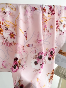 Détail d'un élégant foulard en soie aux motifs floraux roses et pompons dorés