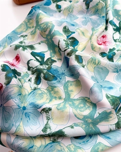 Detailed macro view showing the silky texture and elegant blue floral print of the scarf