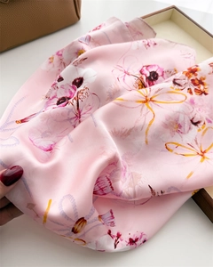 Détail d'un foulard en soie rose avec motifs floraux et texture satinée brillante