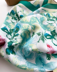 Detail of soft silk floral scarf with elegant blue-green botanical print and rolled edges