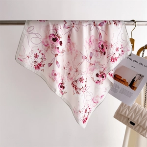 Détail d'un foulard élégant en soie à motifs floraux suspendu sur une barre en métal