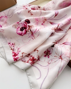 Vue détaillée d'un foulard en soie rose avec motifs floraux et finition satinée