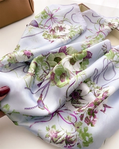 Détail d'un élégant foulard en soie bleu clair avec des motifs floraux blancs et verts
