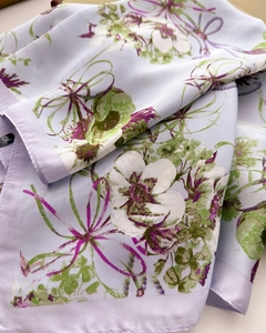 Détail d'un foulard en soie montrant l'imprimé fleuri et la texture satinée avec bords