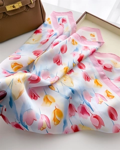 Dettaglio di un foulard di seta bianca con stampa floreale di tulipani e bordi rosa orlati