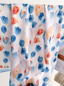 Dettaglio di sciarpa in seta con stampa di tulipani blu e arancio su tessuto bianco fine