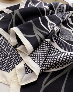 Makrodetail eines Seidenschals mit schwarz-beigen geometrischen Rosendrucken und glatter Textur