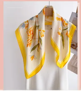 Detail of silk scarf with orange floral print and yellow borders on a white dress