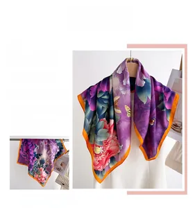 Detail view of purple silk scarf featuring peony patterns and orange contrast borders
