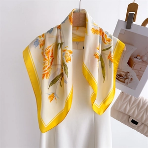 Elegant silk scarf with yellow tulip print and vibrant borders on a white dress