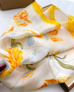 Detail of silk scarf showing orange tulip prints and smooth satin fabric texture