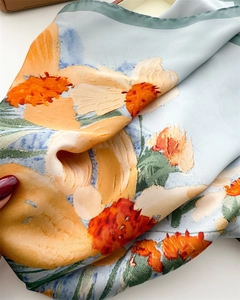 Detail of light blue silk scarf with orange floral print and fine rolled edges