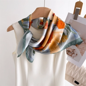 Elegant silk scarf with floral prints in orange and blue tied on a stylish wooden hanger