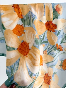 Detail of floral silk scarf with vibrant orange flowers on sky blue fabric background