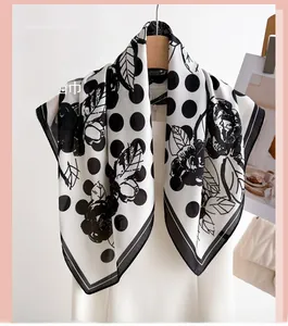 Dettaglio di un foulard in seta bianco e nero con motivi floreali a pois e foglie