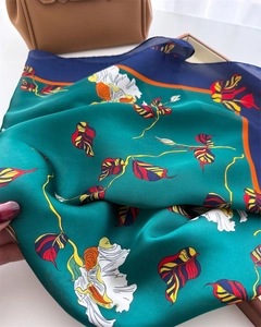Close-up of printed silk scarf with floral patterns draped on a luxury designer handbag