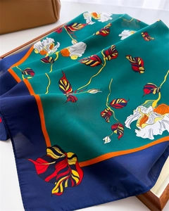 Close-up of vintage silk scarf with green floral print and elegant satin texture on display