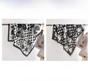 Dettaglio di foulard in seta a fiori e pois neri e bianchi appesi su un supporto