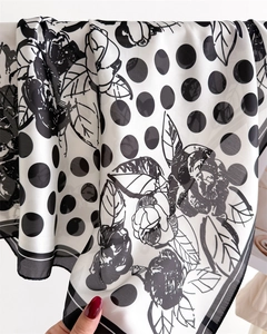 Dettaglio macro di un foulard in seta semitrasparente con pois, fiori e bordi a righe